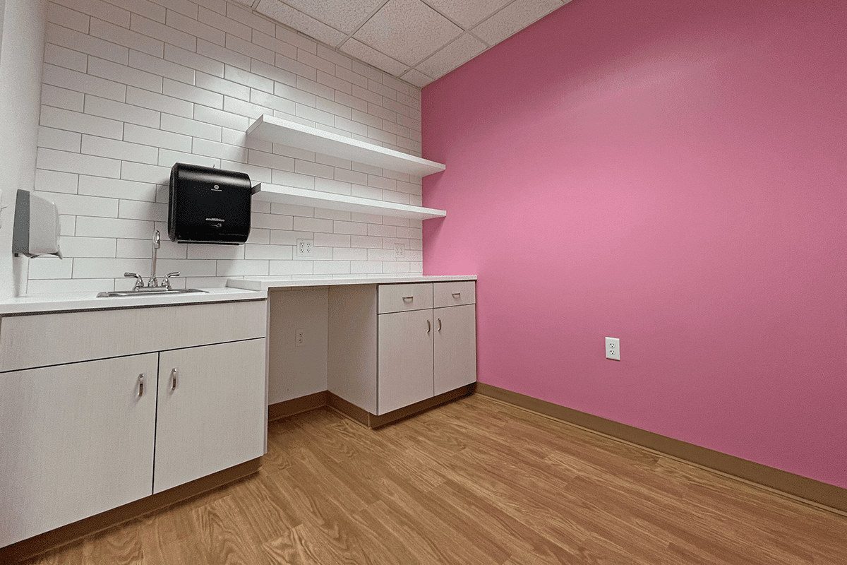 room with pink wall and kitchenette