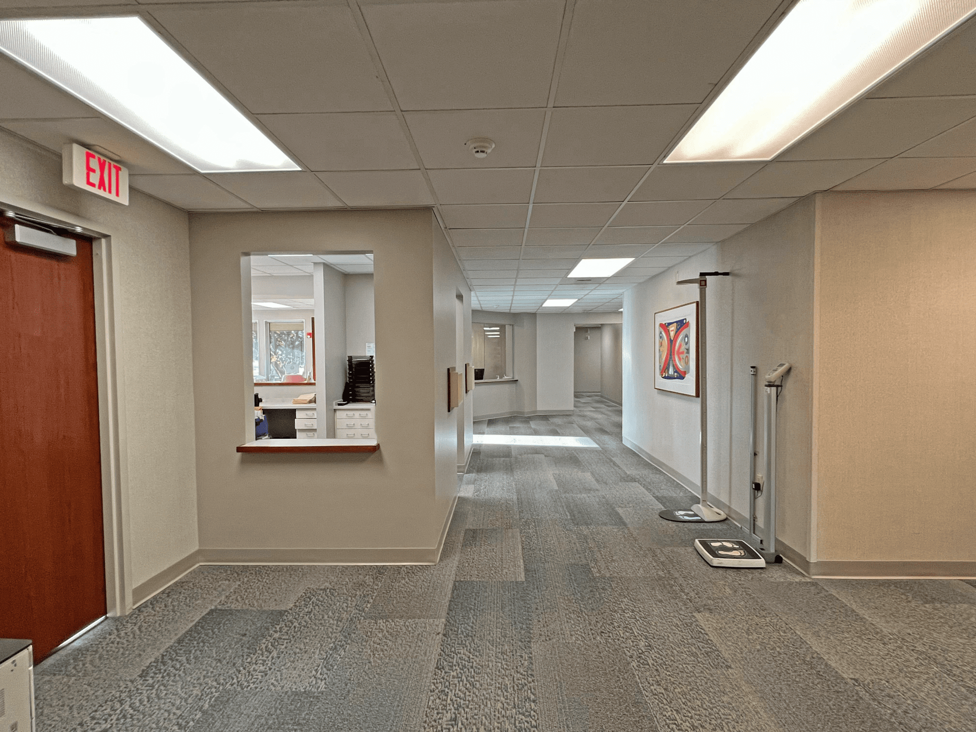 A hallway in a medical office, two height and weight measuring devices are shown