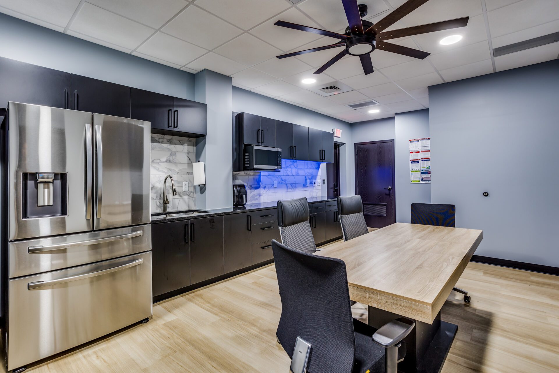 Kitchen and break room with a fridge, microwave, sink, along with a small conference table and chairs.