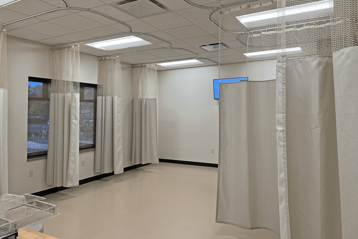 Empty room with multiple privacy curtains hanging from the ceiling for infusion patients.