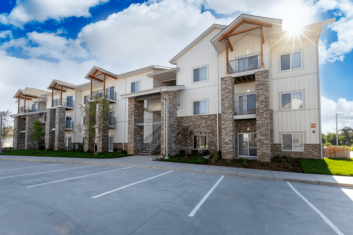 A modern apartment building with a parking lot in front.