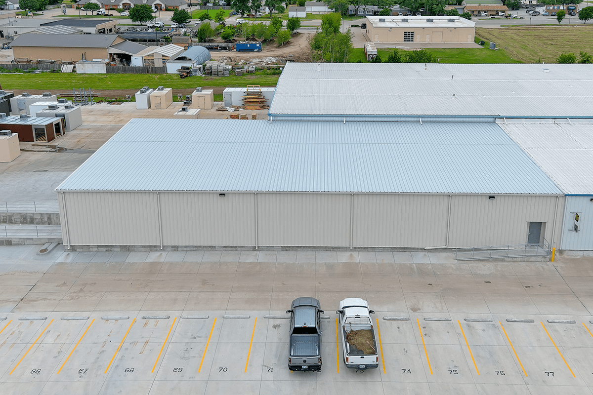 Commercial warehouse with a gray facade, loading bays, and two pickup trucks parked in front.